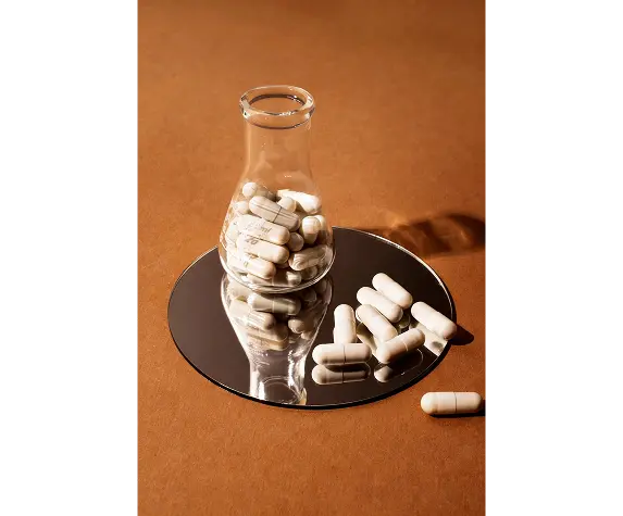 Laboratory flask with pills on a mirror